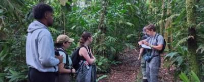 Students standing along a path in woods.